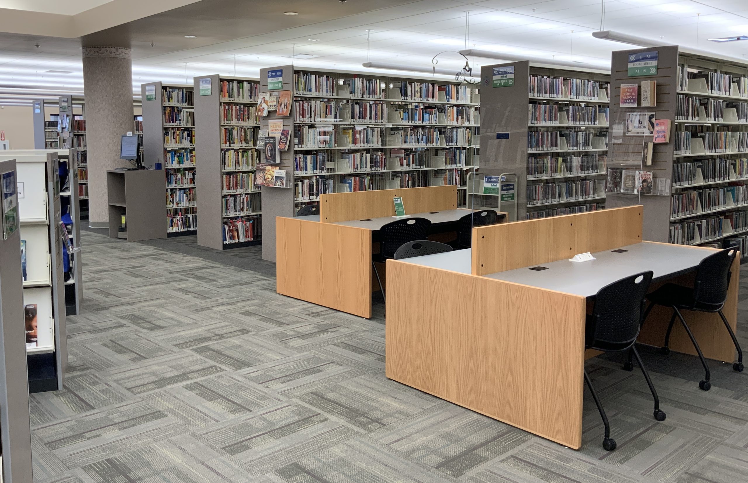 Library interior with bookshelves, study desks, and chairs.