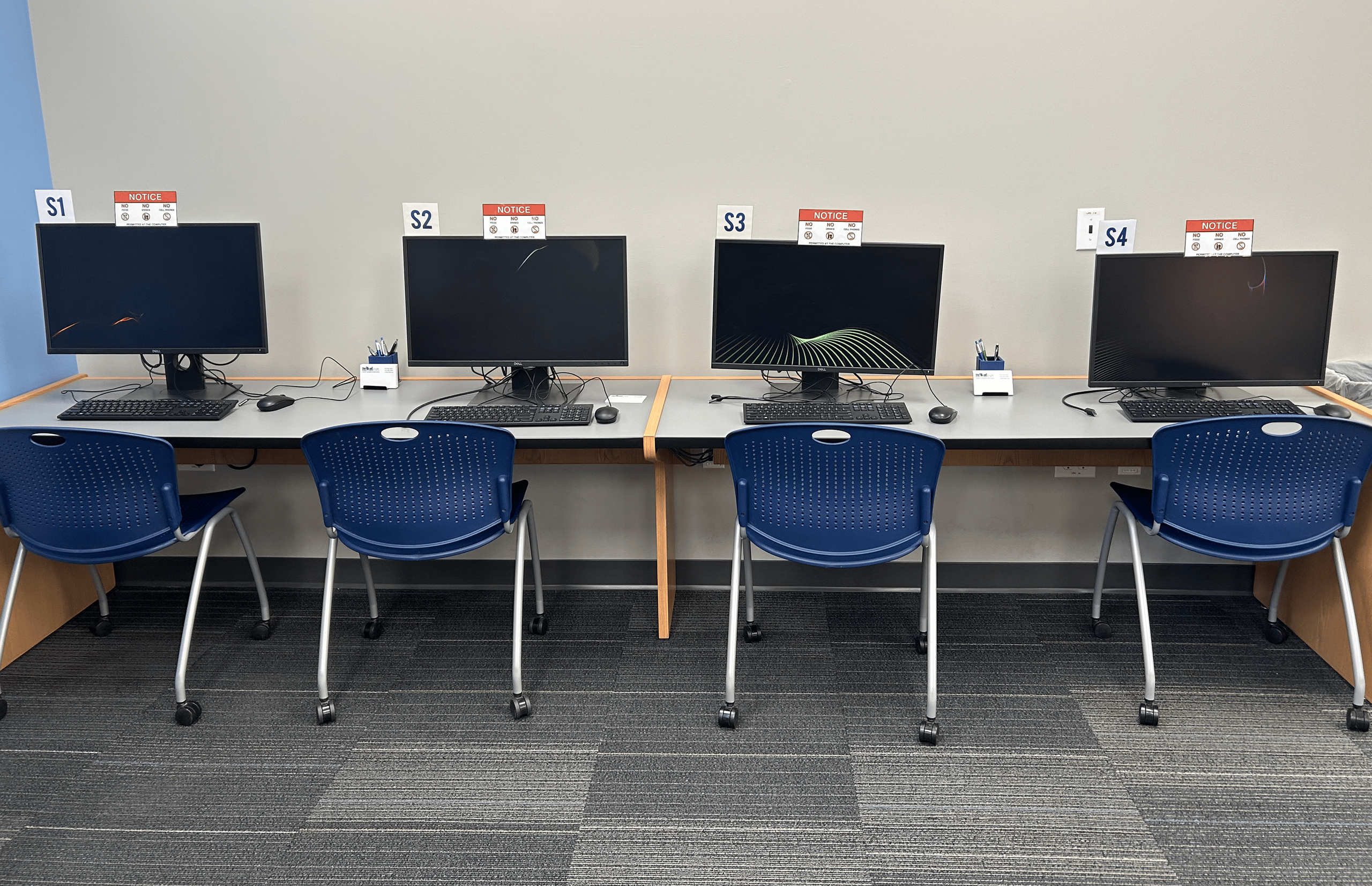 Four computers with rolling chairs labeled "S1", "S2", "S3" , and "S4".