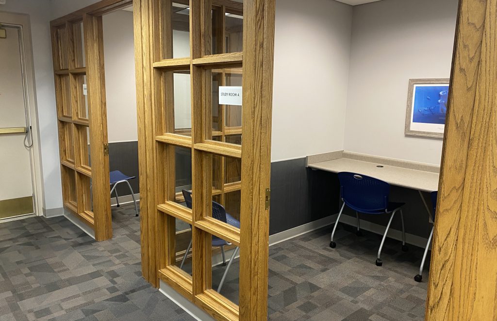 Study rooms with windows, desk, chairs, and framed artwork on wall.